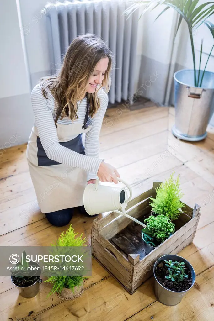 Smiling woman at home watering plants