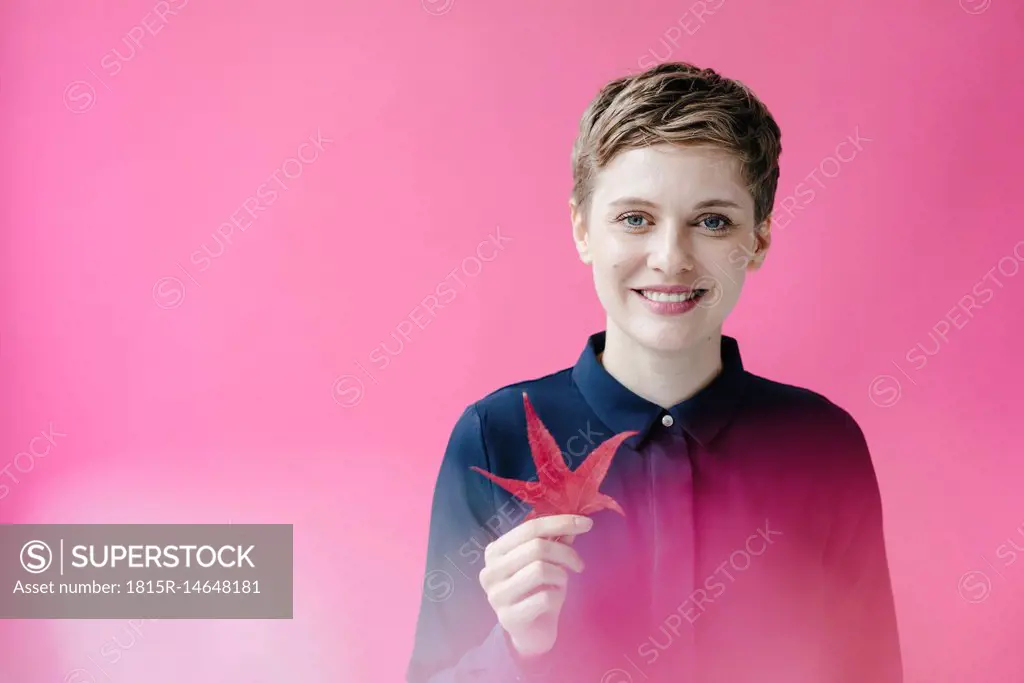 Portrait of smiling woman holding autumn leaf
