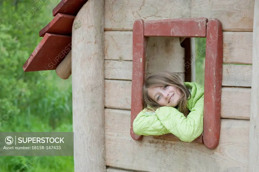 Germany, Bavaria, girl looking outside of the window of a wendy house