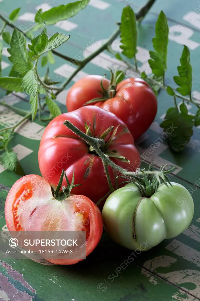 Whole and sliced Silesian raspberry tomatoes (Solanum lycopersicum), studio shot