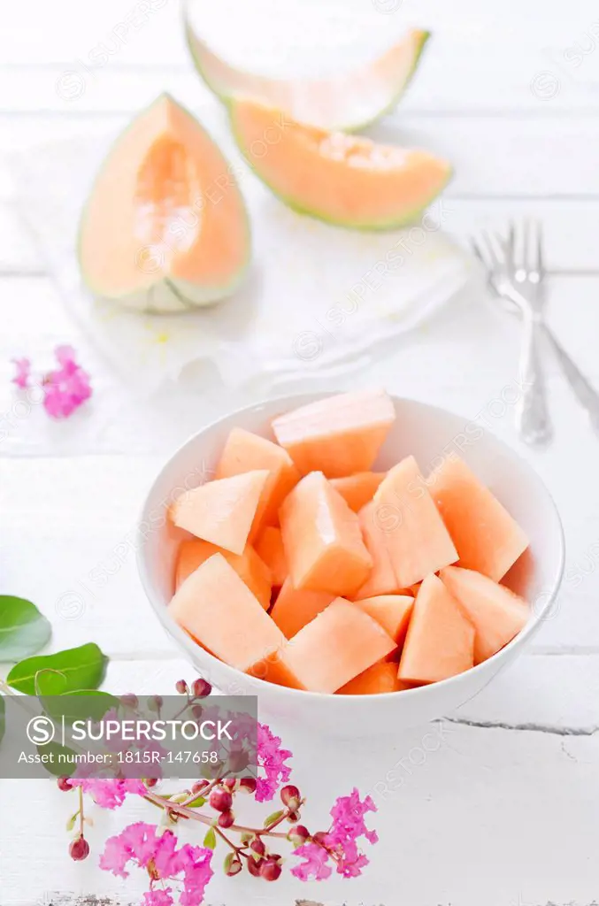 Pieces and slices of charentais melon on white wooden table