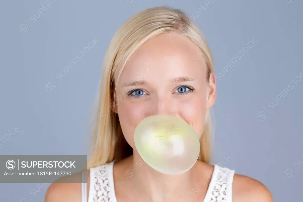 Young woman blowing bubble gum