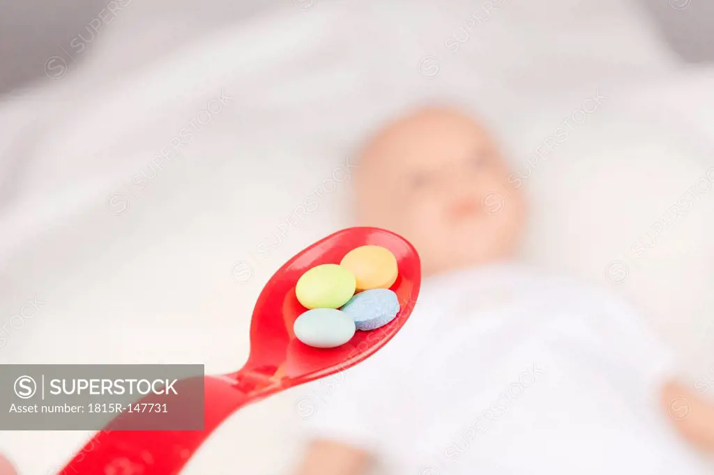 Spoon with tablets and baby doll in background