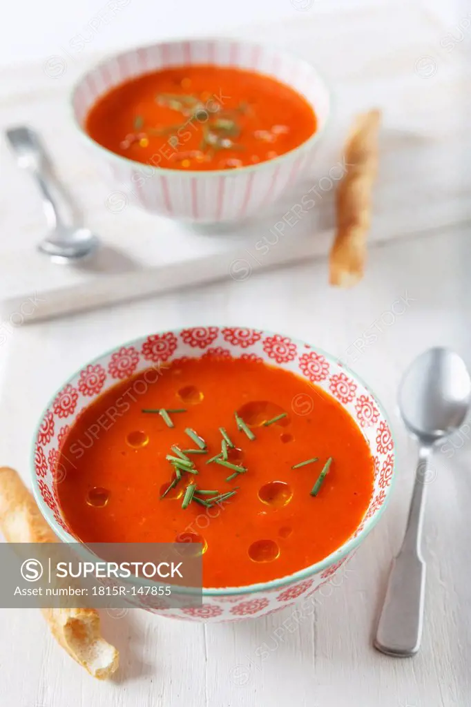 Cold bell pepper soup with bread sticks, close up