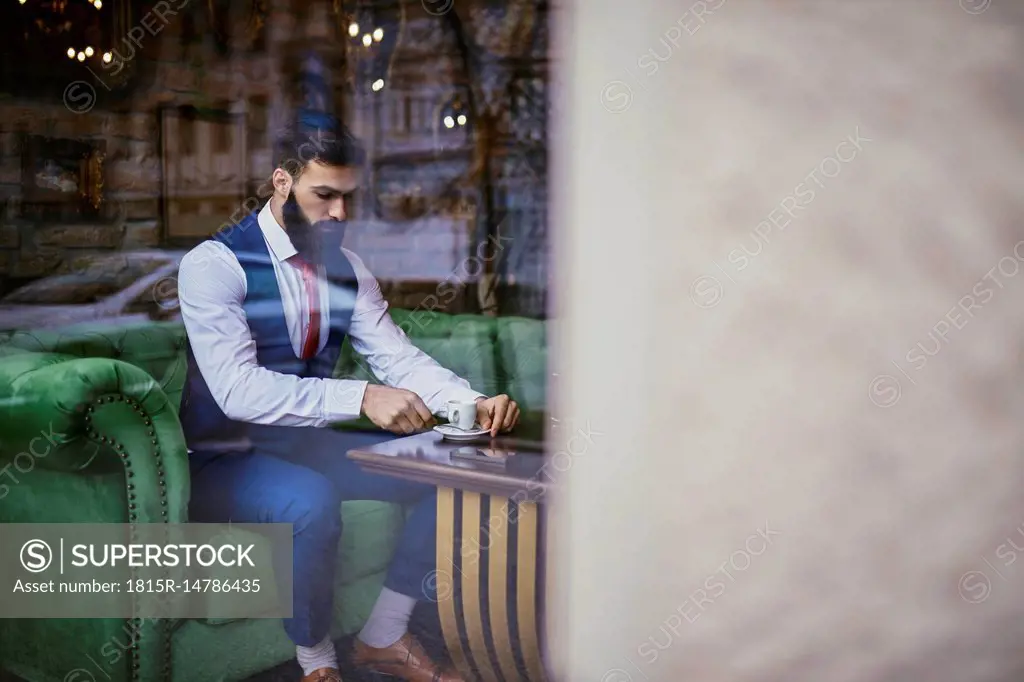 Fashionable young man sitting on couch in a cafe