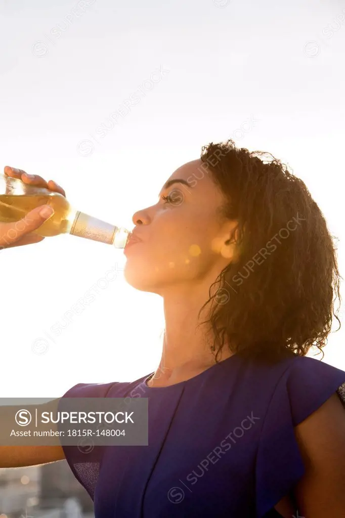 Germany, Berlin, Young woman drinking beer