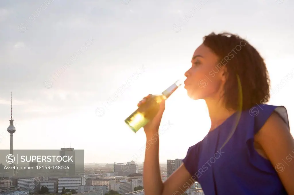 Germany, Berlin, Young woman drinking beer