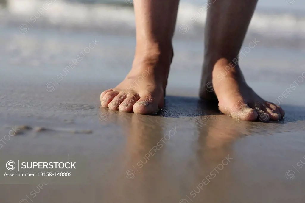 Germany, Lower Saxony, East Frisia, Langeoog, feet of a woman at the beach