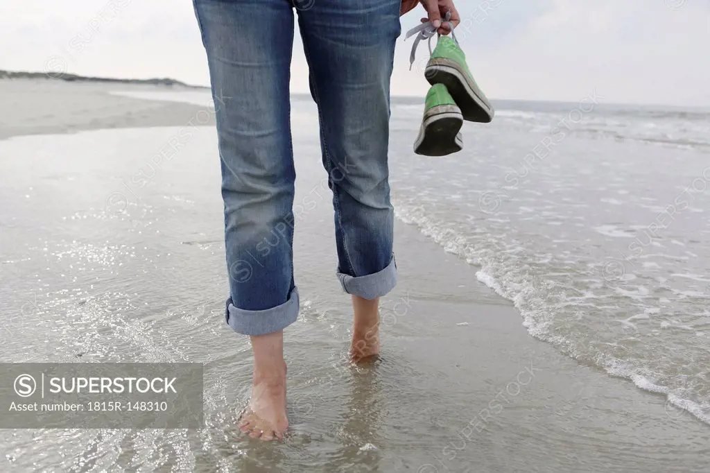 Germany, Lower Saxony, East Frisia, Langeoog, legs of a woman walking at the beach