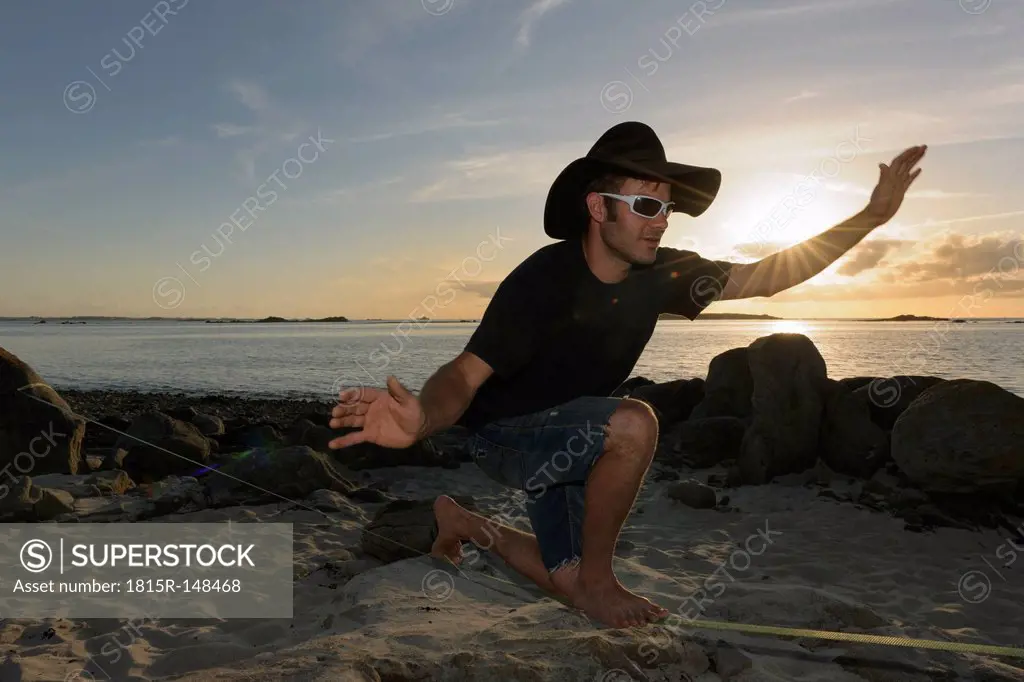 France, Bretagne, Landeda, Man balancing on slackline on beach