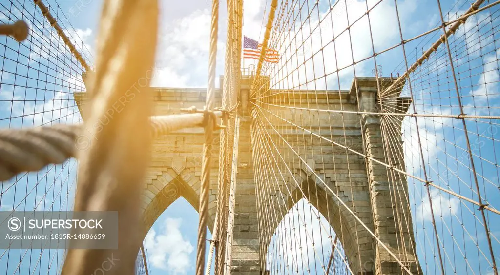 USA, New York, Brooklyn, Close up of Brooklyn Bridge metal cables and arches with american flag on the top
