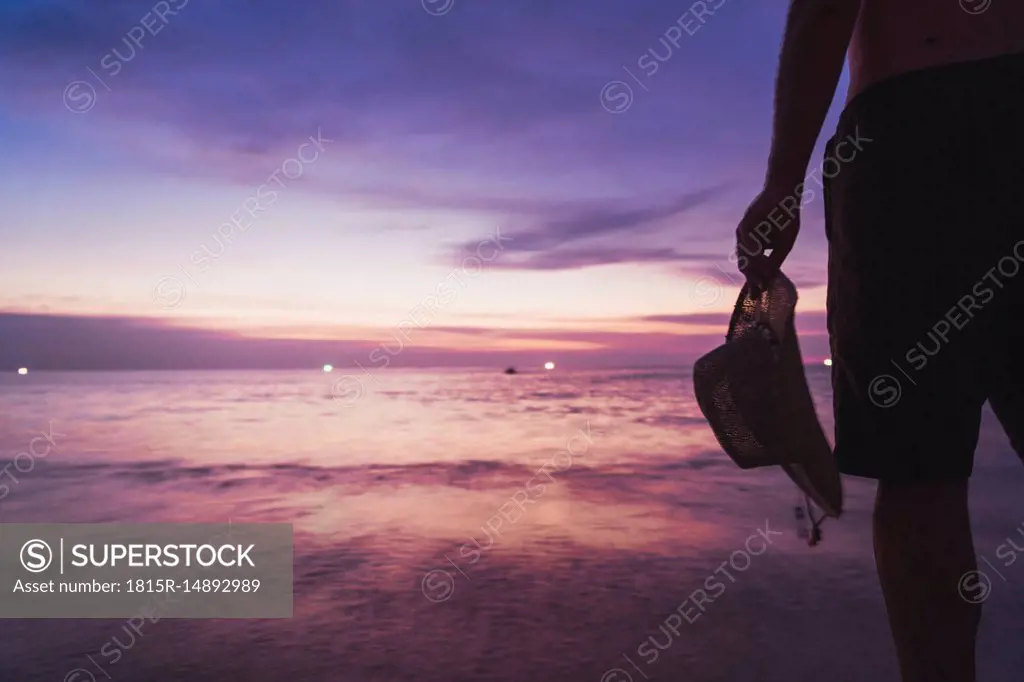 Thailand, Phuket, man standing at seaside by sunset, partial view