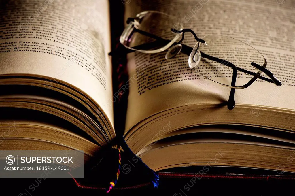Opened book with bookmark and reading glasses
