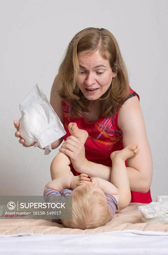 Mother changing diapers of son, studio shot
