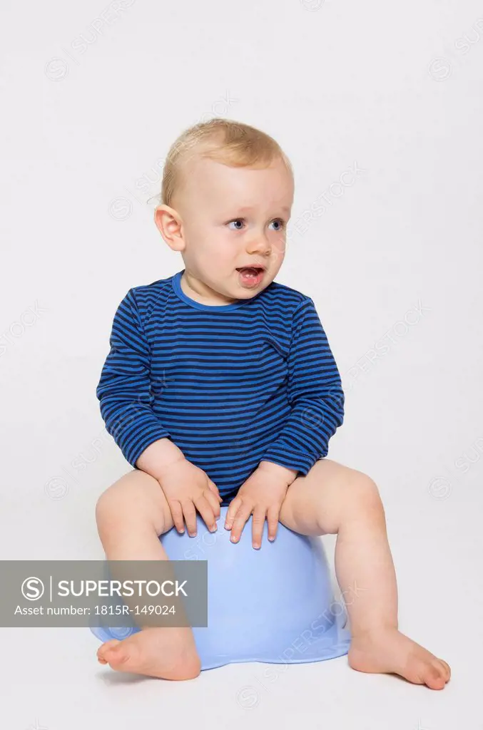 Baby boy sitting on his potty, studio shot