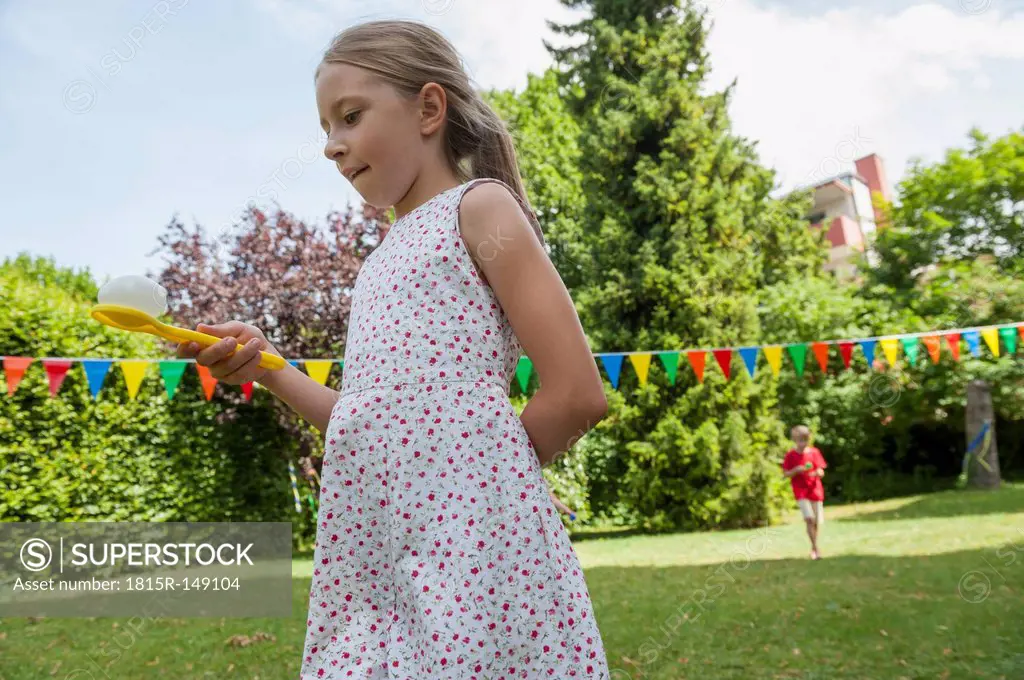 Children having a spoon and egg race in garden on a birthday party