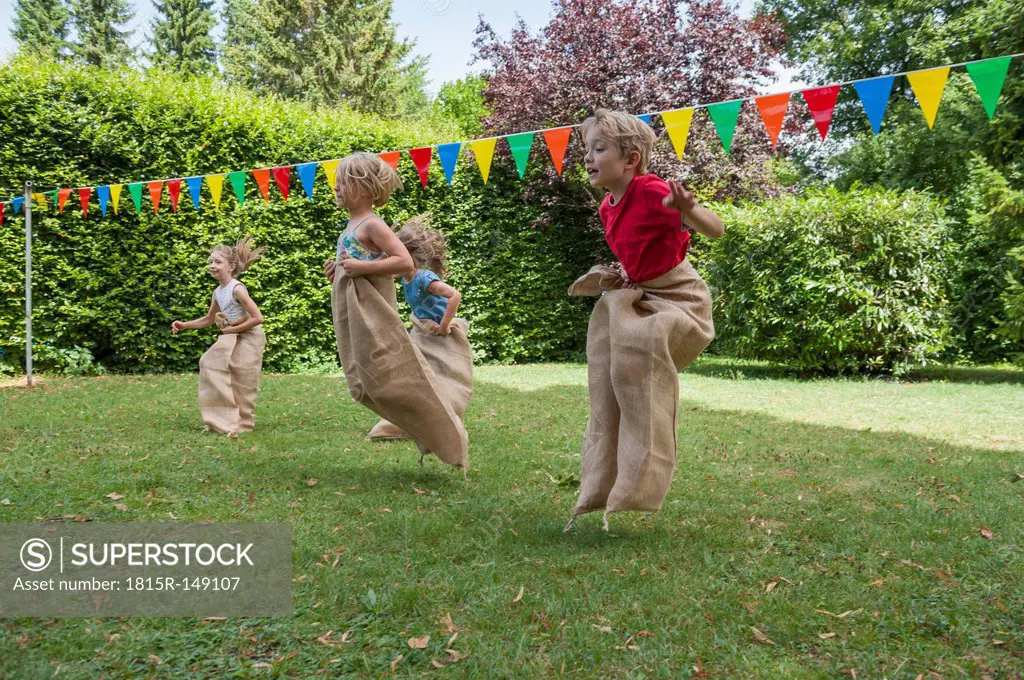 Children having a sack race in garden on a birthday party
