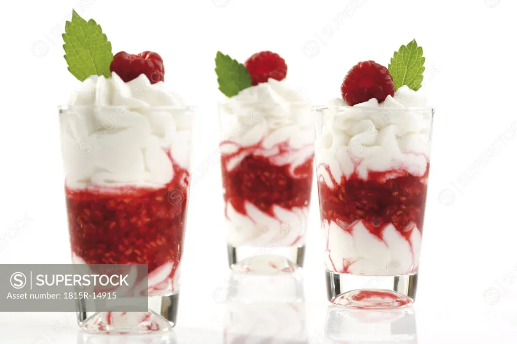 Raspberries with whipped cream in glass, close-up