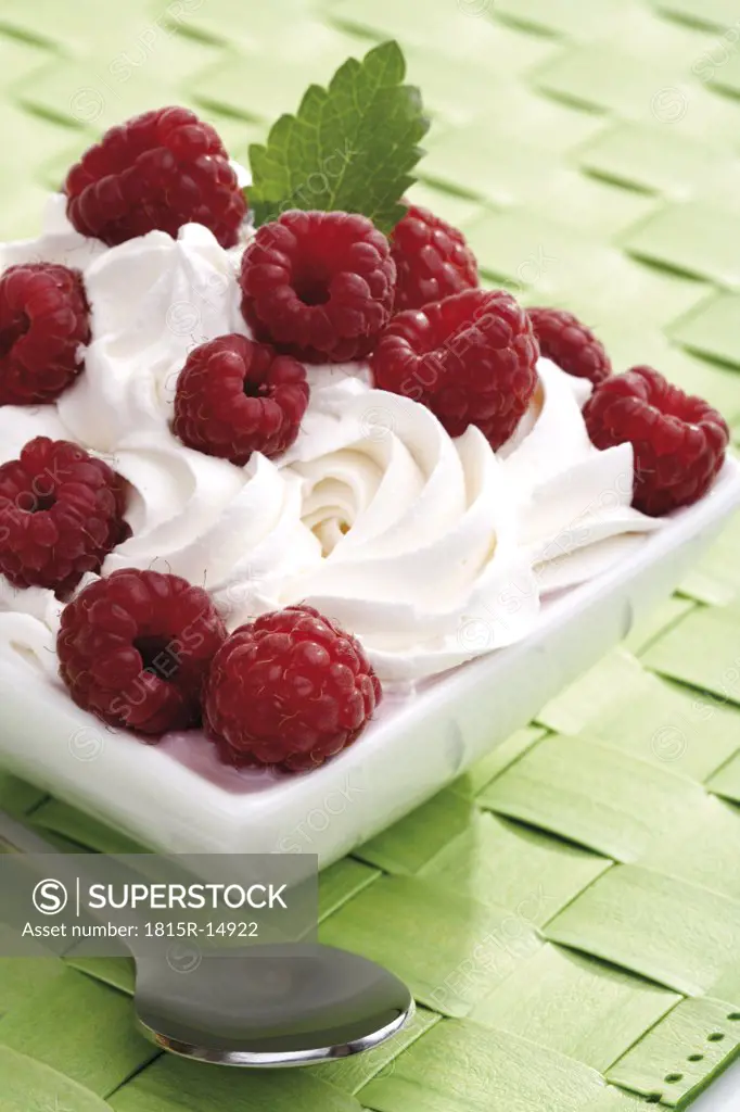 Rasberries on whipped cream in bowl, close-up