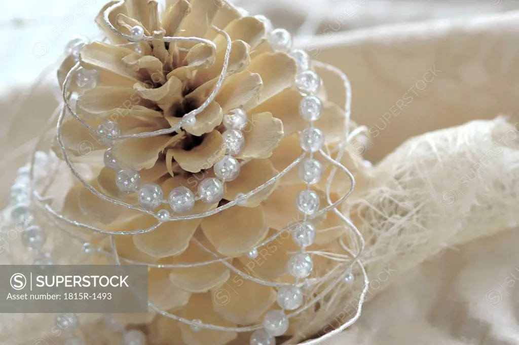 Christmas decoration with fir cone and pearl string, close-up