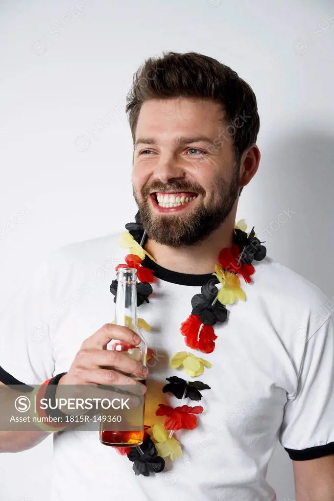 Smiling man in soccer jersey holding beer bottle