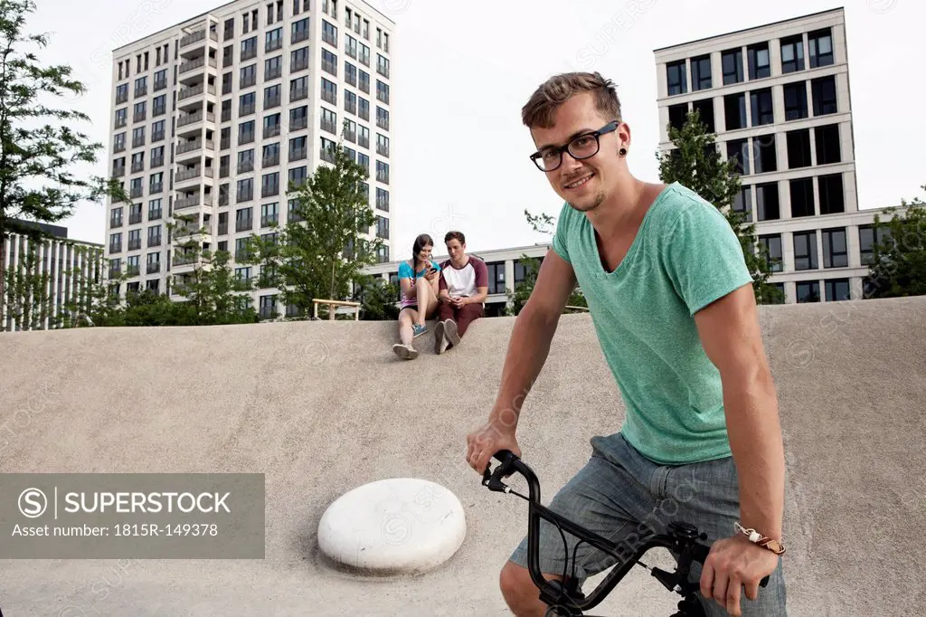 Germany, Bavaria, Munich, Young man with BMX bicycle