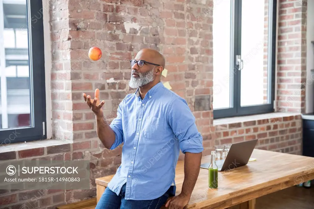 Freelancer throwing apple in the air in a loft