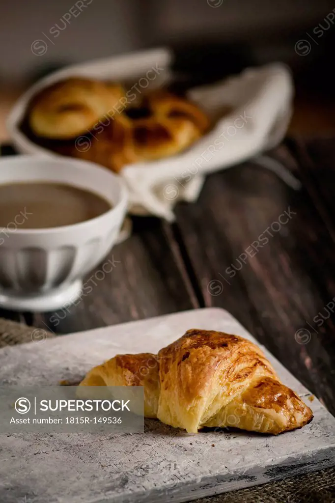 Croissants with milk coffee and jam on wooden board, studio shot