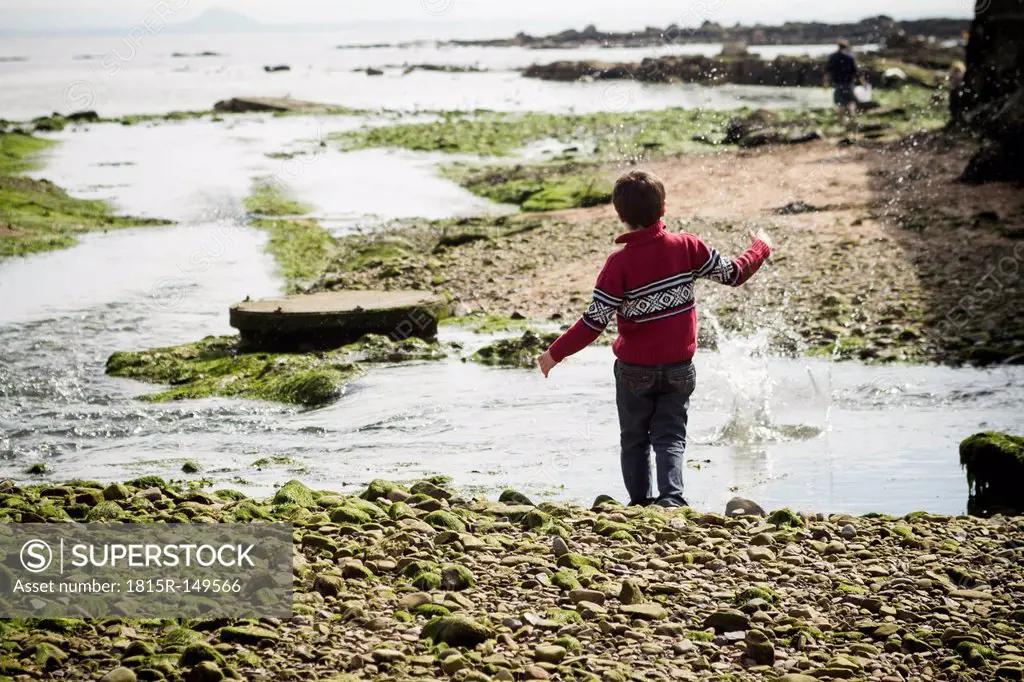Great Britain, Scotland, Fife, Anstuther, boy at the beach throwing stones into water