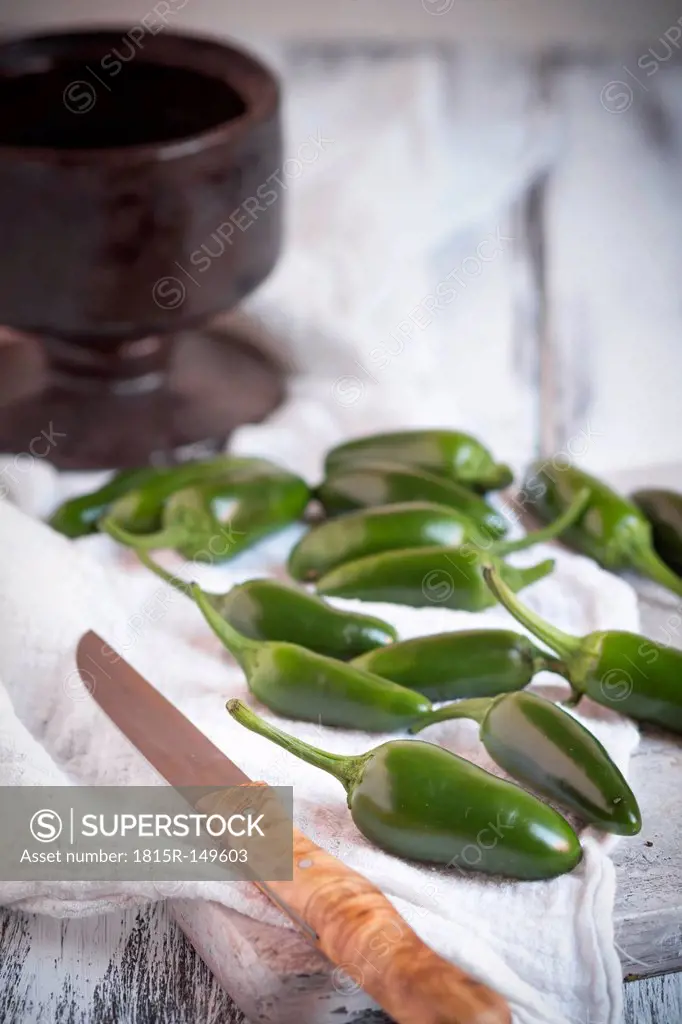 Green Jalapeno-Chilis (Capsicum annuum) on a white chopping board, studio shot