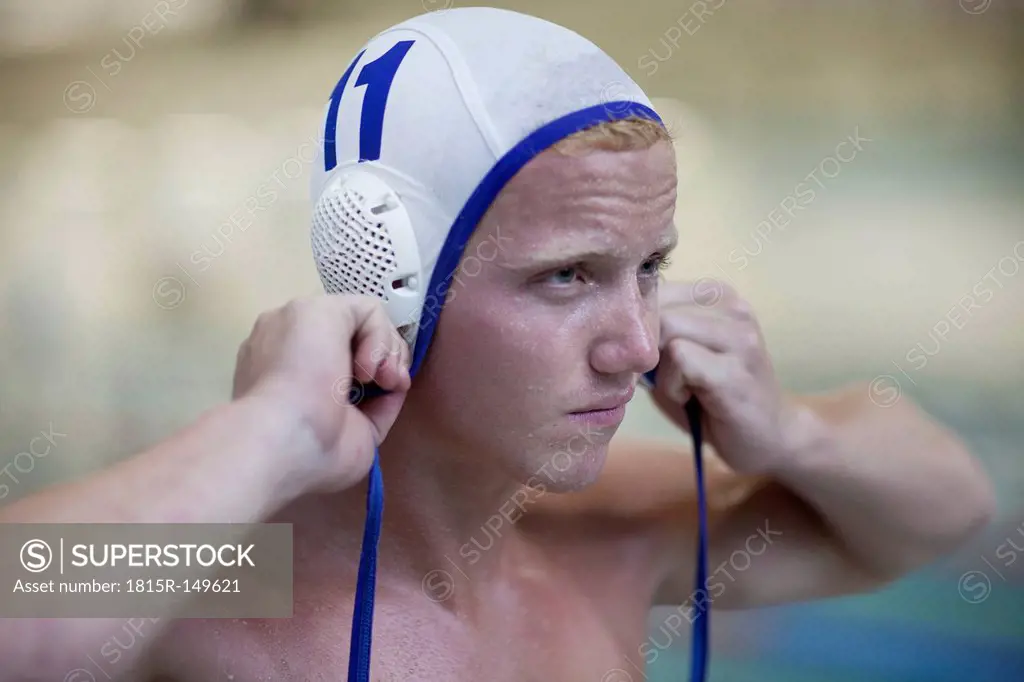 Water polo player outside pool putting on cap