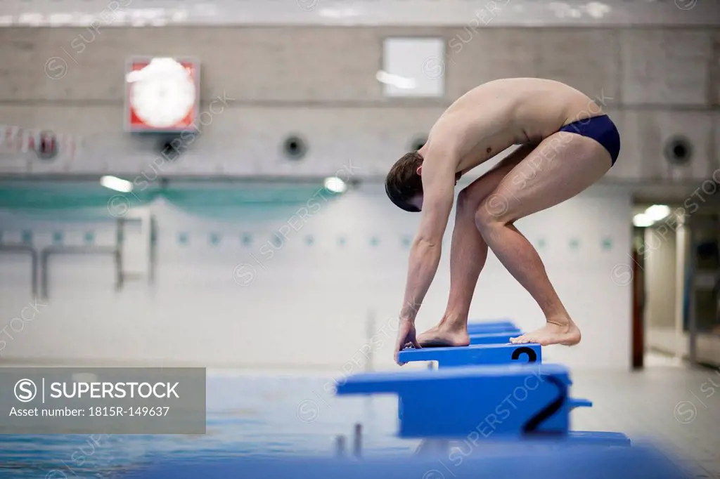 Swimmer on starting block at indoor swimming pool