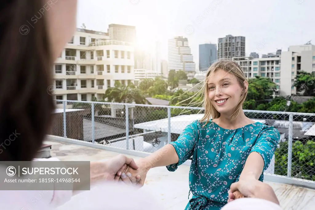 Young woman holding hands with boyfriend on rooftop