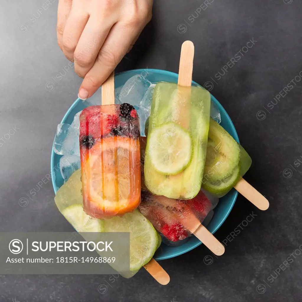 Woman's hand taking orange berry popsicle