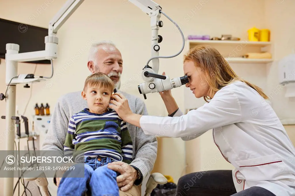 ENT physician examining ear of a boy sitting on grandfather's lap