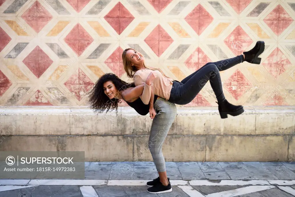 Laughing woman carrying her best friend piggyback