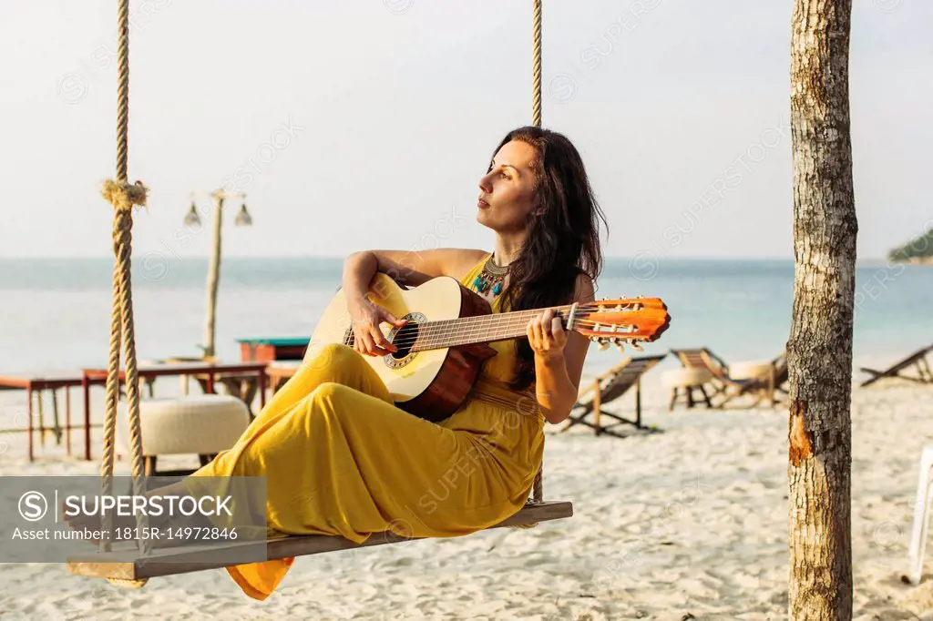 Thailand, Koh Phangan, woman playing guitar at the beach