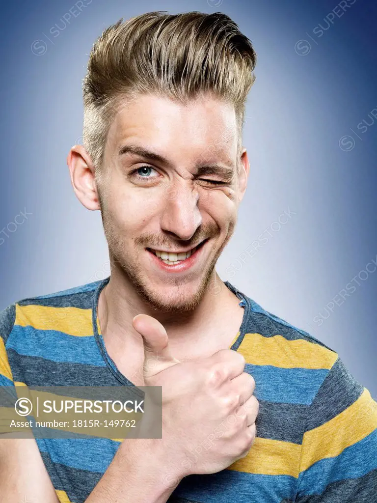 Portrait of young man with thumb up, studio shot