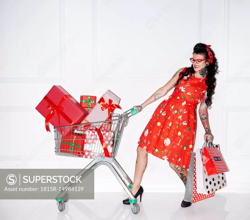 Tattooed woman with shopping bags and shopping cart full of gifts