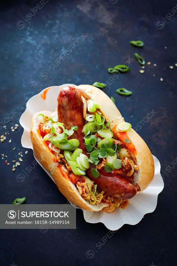 Asian hot dog, fried sausage, spicy chinese cabbage, hot chili sauce, spring onions, cress, bun