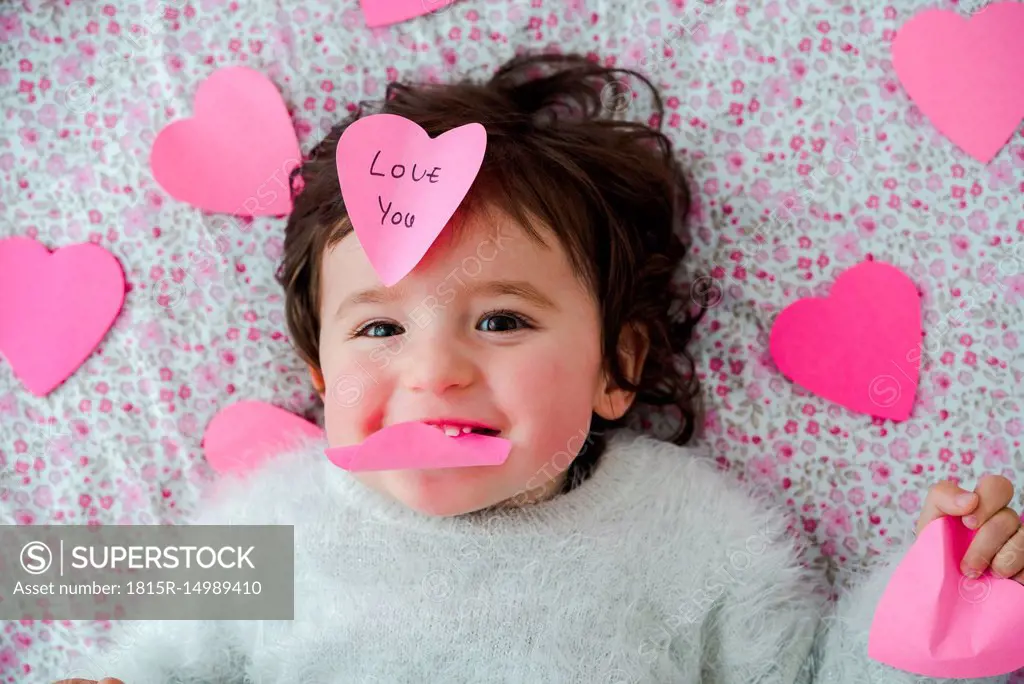 Portrait of baby girl with pink heart-shaped post it stickers