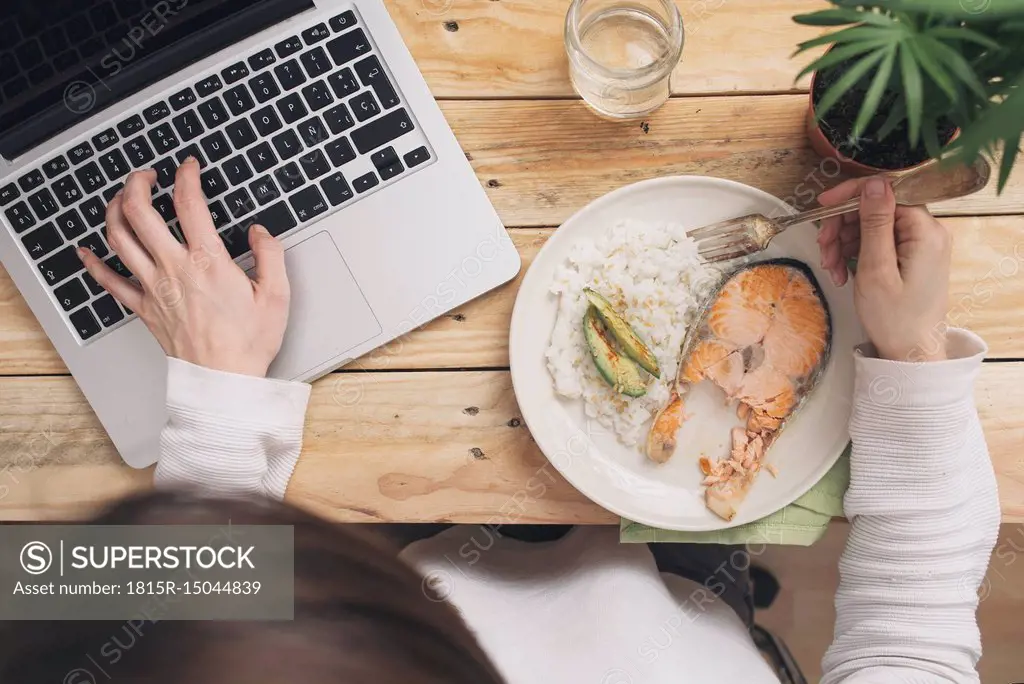 Woman having lunch and using laptop
