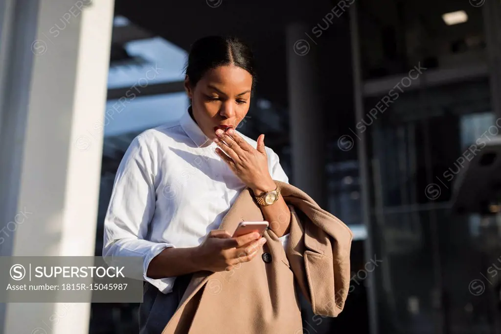 Portrait of shocked businesswoman reading email on her mobile phone