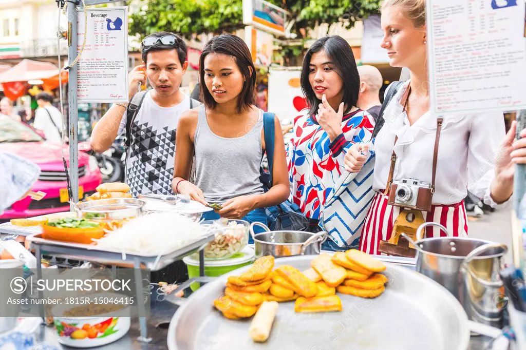 Thailand, Bangkok, Khao San Road, group of friends choosing local food on street market