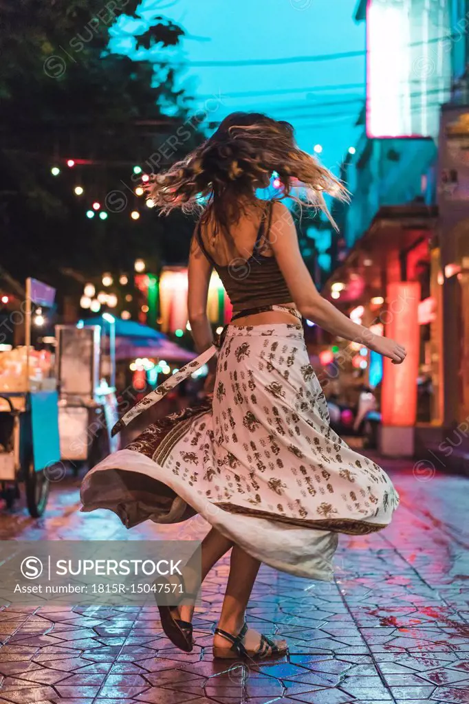 Thailand, Bangkok, young woman in the city dancing on the street at night