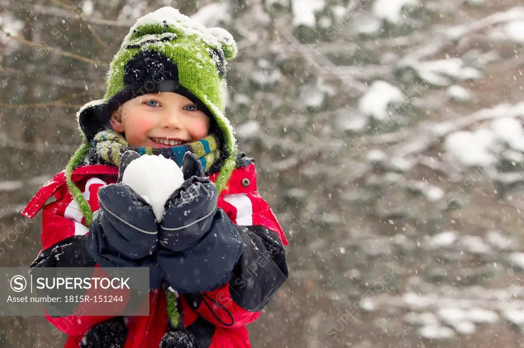 Germany, Munich, Little boy holding snowball