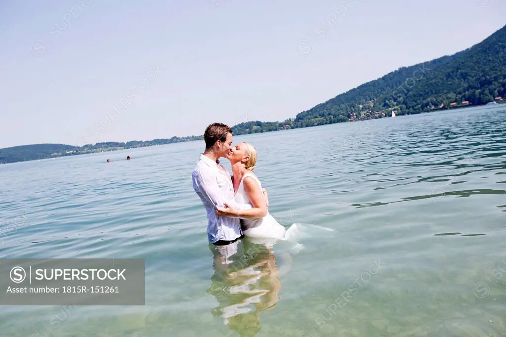 Germany, Bavaria, Tegernsee, Wedding couple standing in lake, kissing