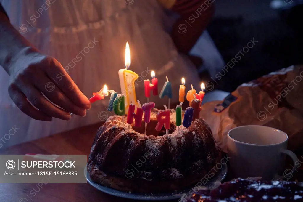 Woman lightning birthday cake candles, partial view