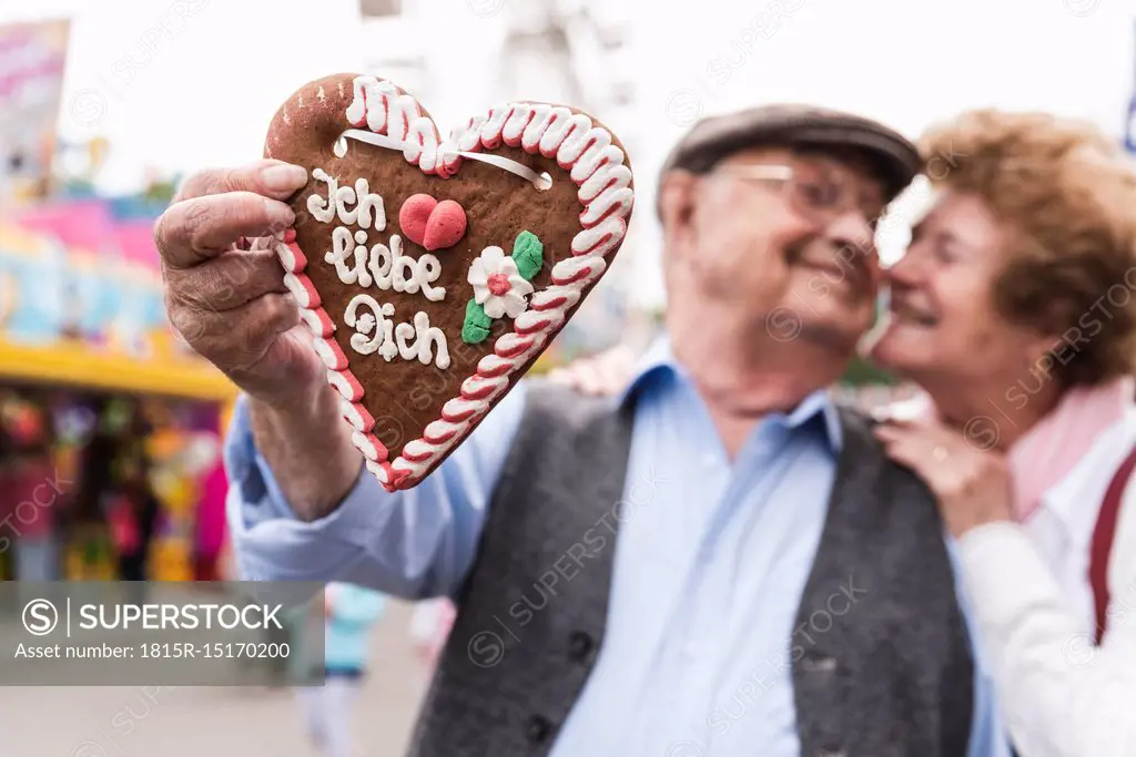 Hand of senior man holding ingerbread heart on fair, close-up