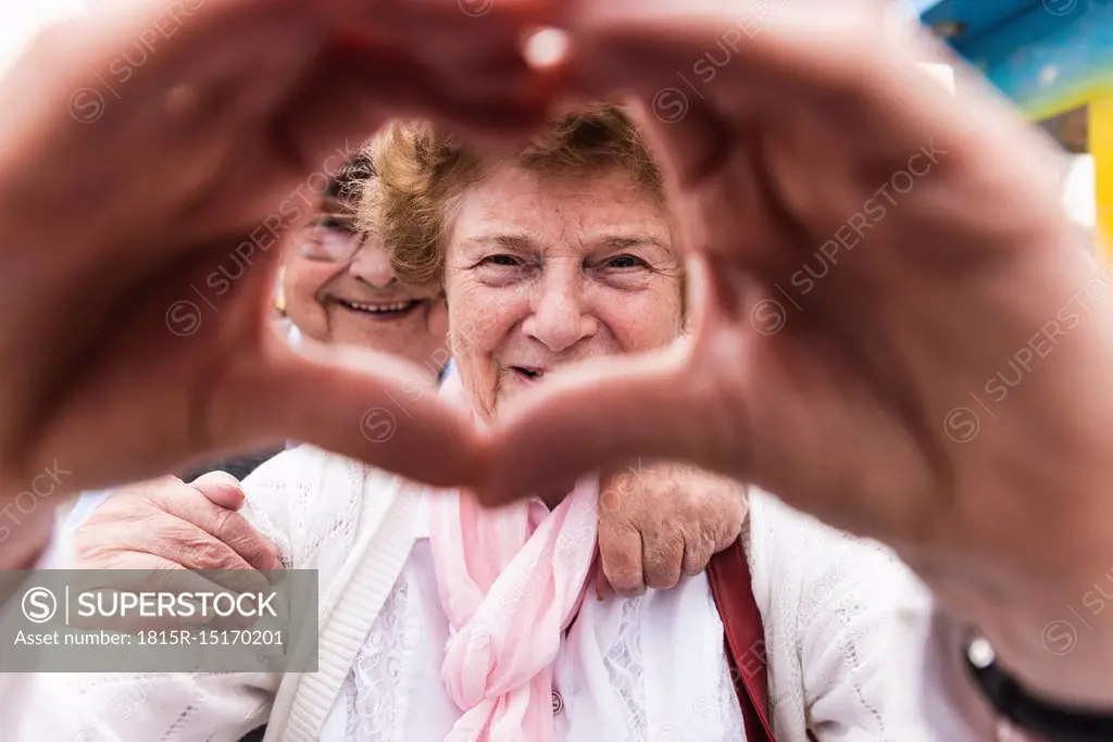 Portrait of happy senior woman shaping heart with her hands